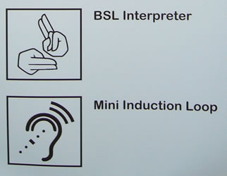 Lower half of the sign outside the Information Desk. The event programme is available in large print, braille and tape formats. Audio description headsets can be collected from the Information Desk. There is a British Sign Language (BSL) interpreter on the stage. Mini induction loops are provided to help people who are partially deaf.